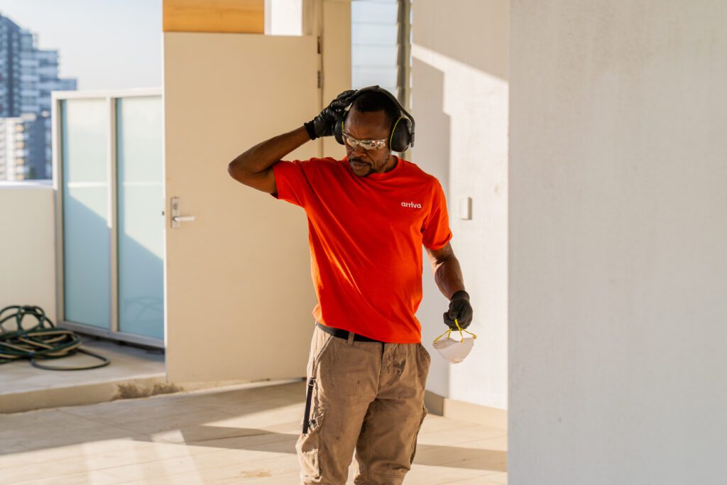 arriva team member adjusting safety earmuffs while holding a protective mask